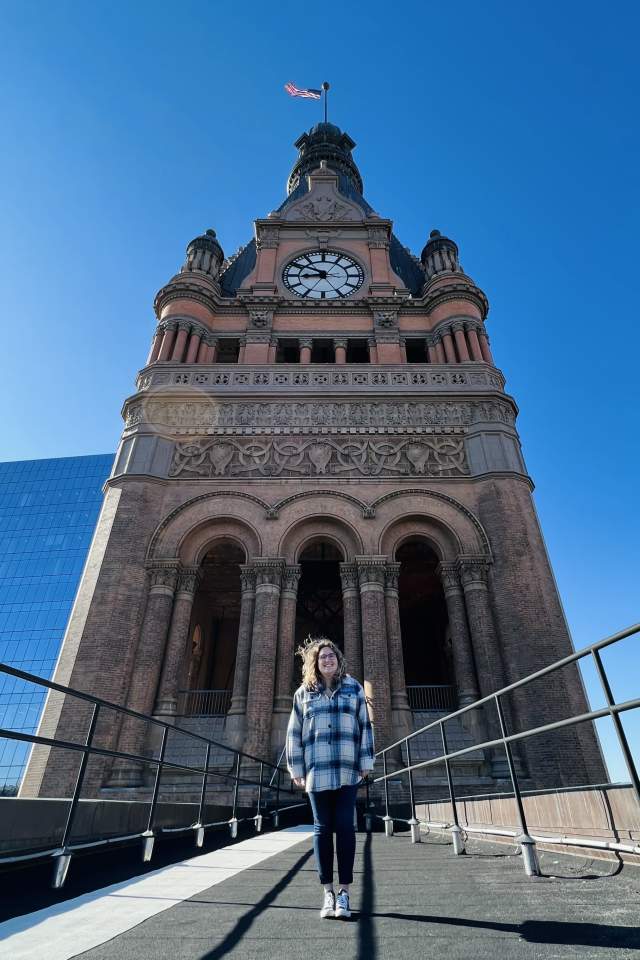 a person standing in the wind in front of Milwaukee City Hall