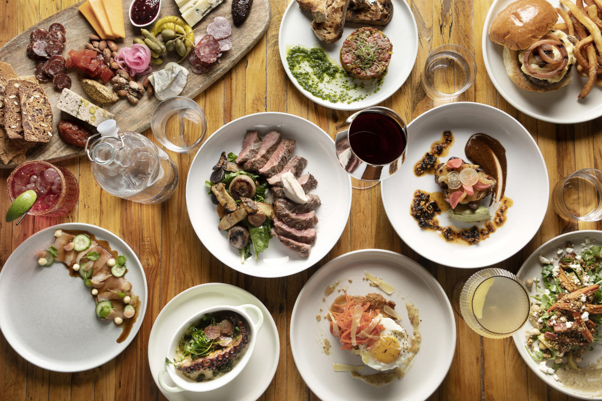 a wide array of food laid out artfully on a wooden table and shot from a birds eye view