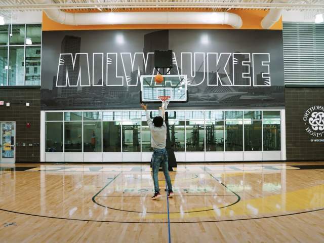 someone shooting a basketball in a Milwaukee Panther branded gym