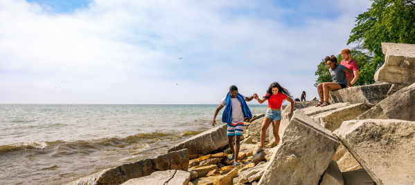 friends climb on beach rocks on the lakefront