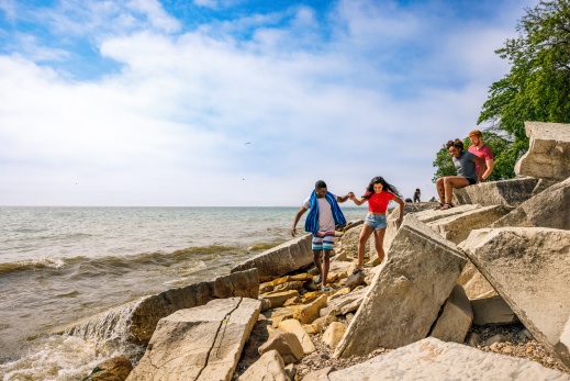 friends climb on beach rocks on the lakefront