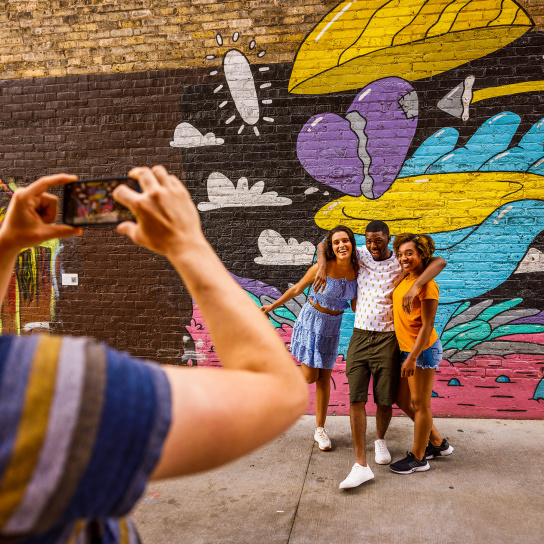 friends taking a picture in front of a colorful mural