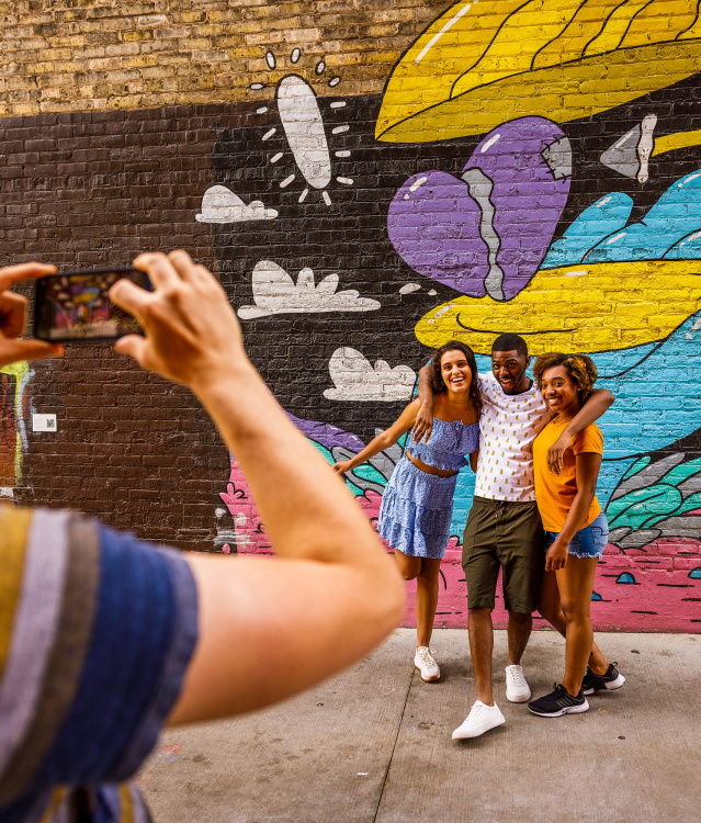 friends taking a picture in front of a colorful mural