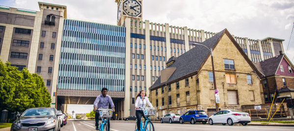 two people using bublr bikes, biking under the clocktower