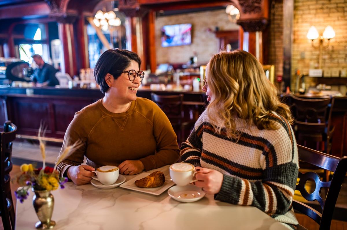 Two women smiling and drinking coffee in a cafe