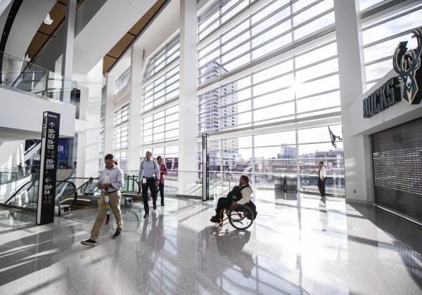 people coming up escalator, man in wheelchair meeting them