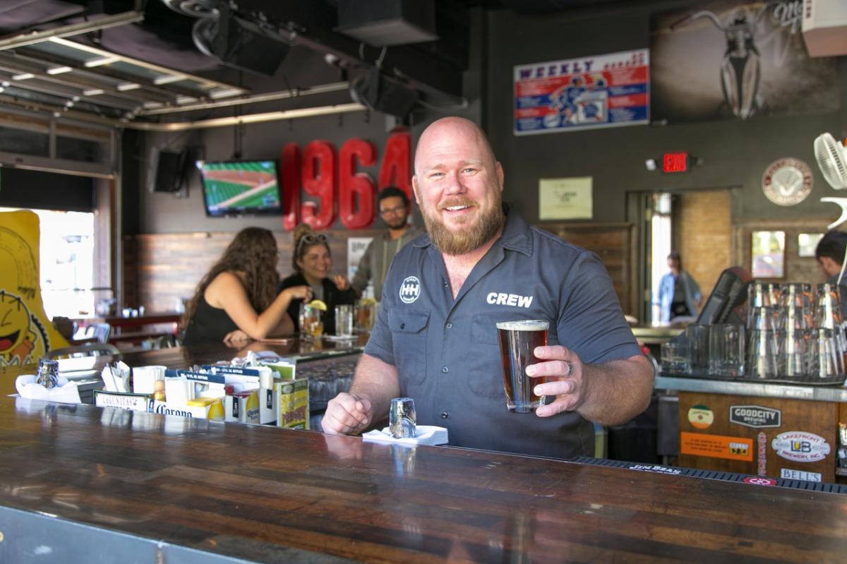 Bartender serving a beer with baseball on a TV in the background at The Garage