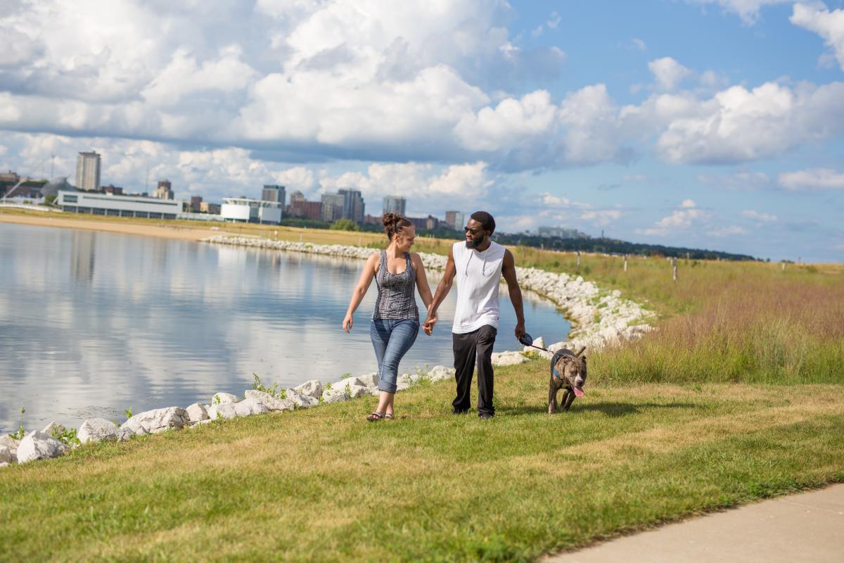 Couple waling a dog along the shores of Lakeshore State Park