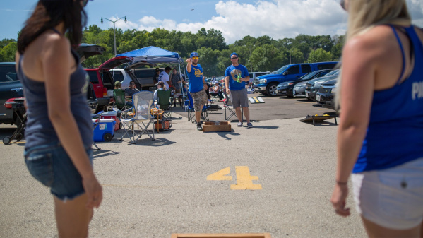 A group of Brewers fans playing a game of corn hole while they tailgate