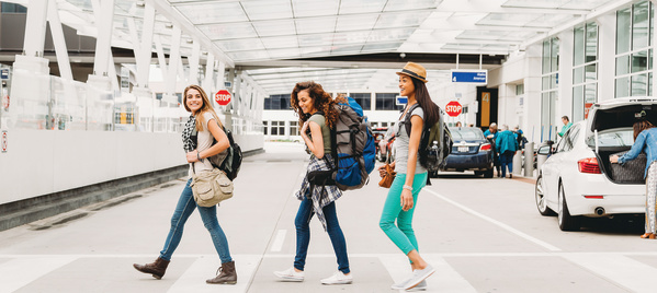 three women smiling after getting baggage and walking out of airport