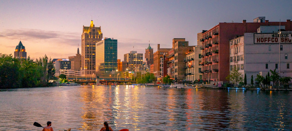 two kayakers on the Milwaukee River overlooking Milwaukee's Historic Third Ward and the skyline