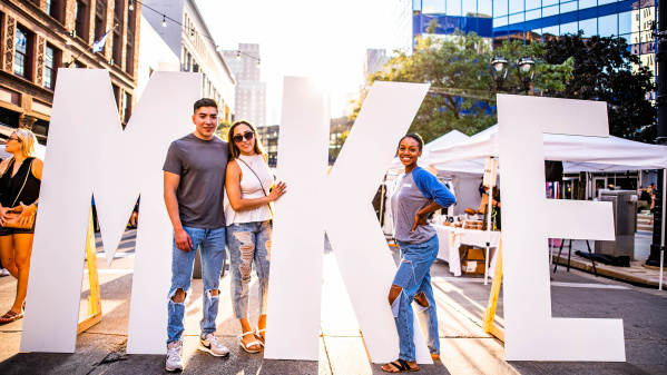 friends posing by big MKE letters at the Westown Night Market