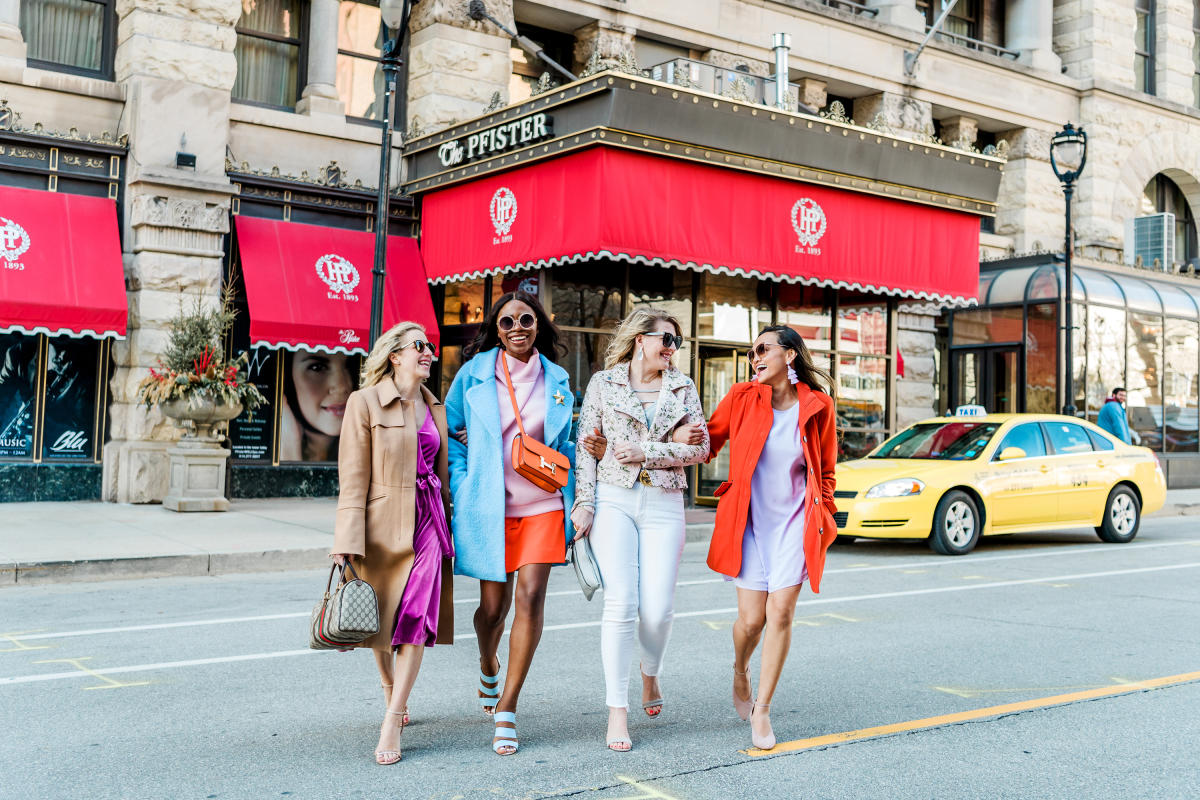 group of friends interlocking arms and walking in front of the Pfister Hotel