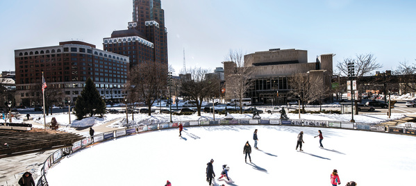 ice skaters at Red Arrow Park with city behind