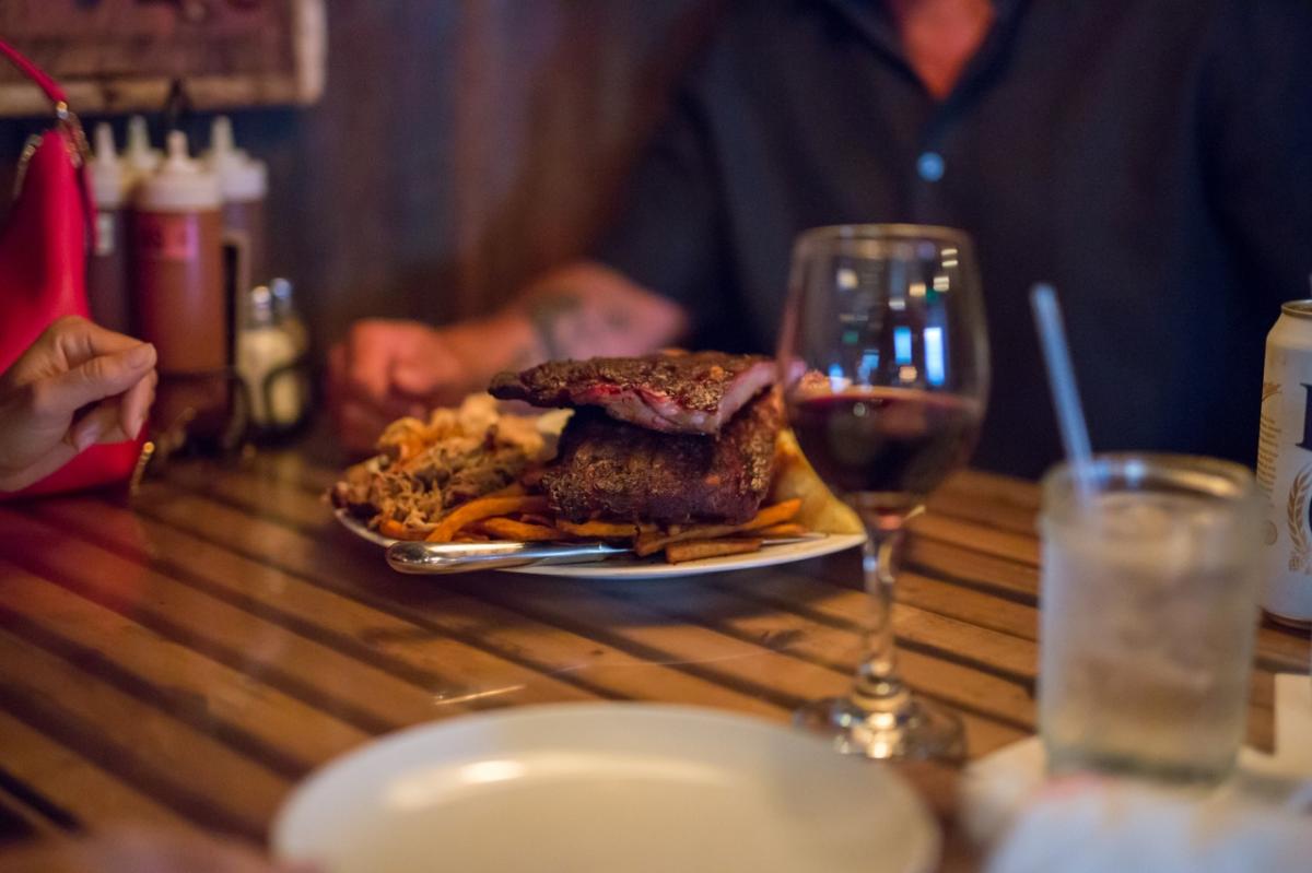 A plate of ribs and fries near a glass of red wine at Smoke Shack Milwaukee