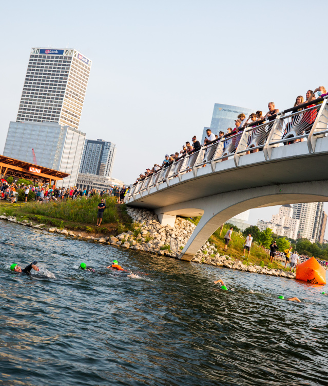 wide shot of USA Triathlon atheletes jumping into the lagoon next to Discovery World