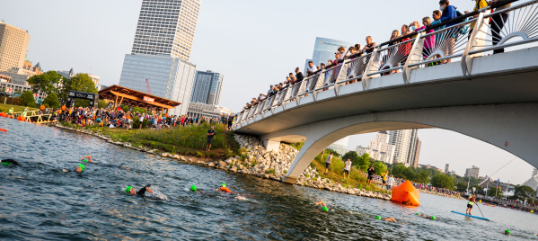 wide shot of USA Triathlon atheletes jumping into the lagoon next to Discovery World